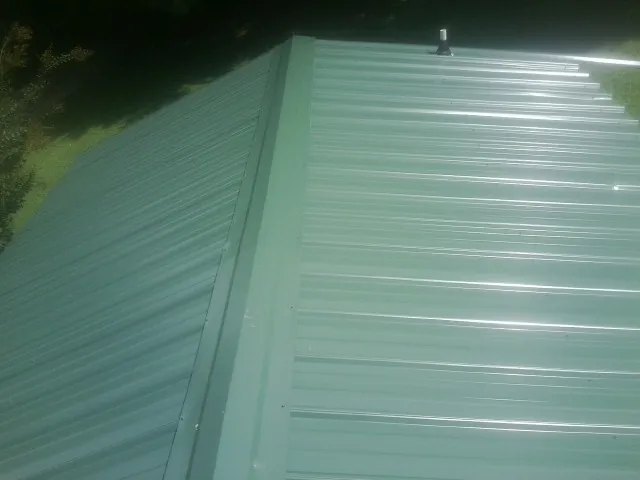 New green metal panels meeting at the ridge of a roof — Flat Roof Repair work by our crew in Kemah