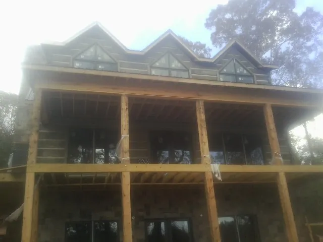 Dormers and porch framing on a large log home under construction — Roof Coating work by our crew in Kemah