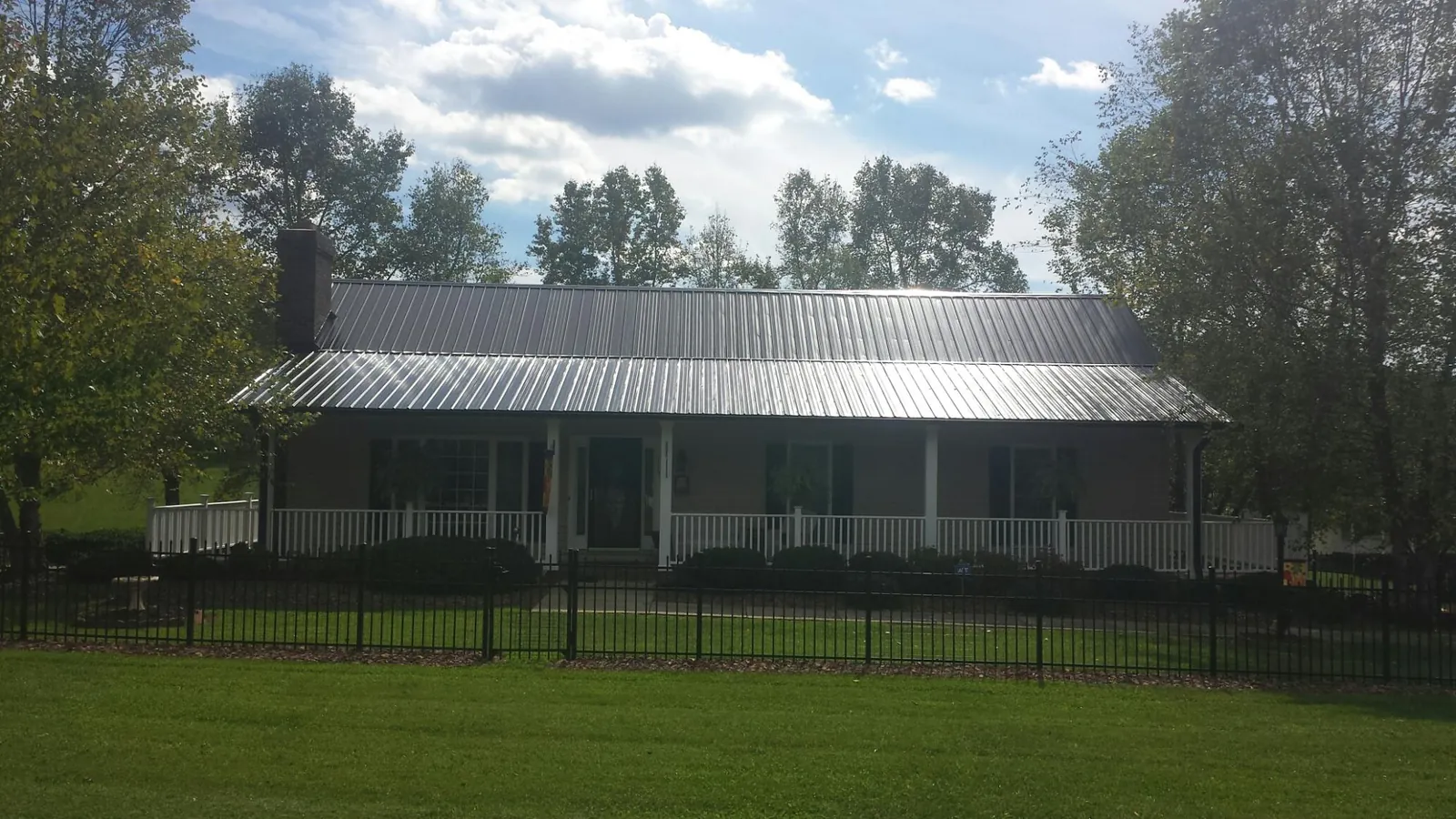 Gray metal roof on a brick ranch with a full width front porch — Gutter Guard Installation work by our crew in Kemah