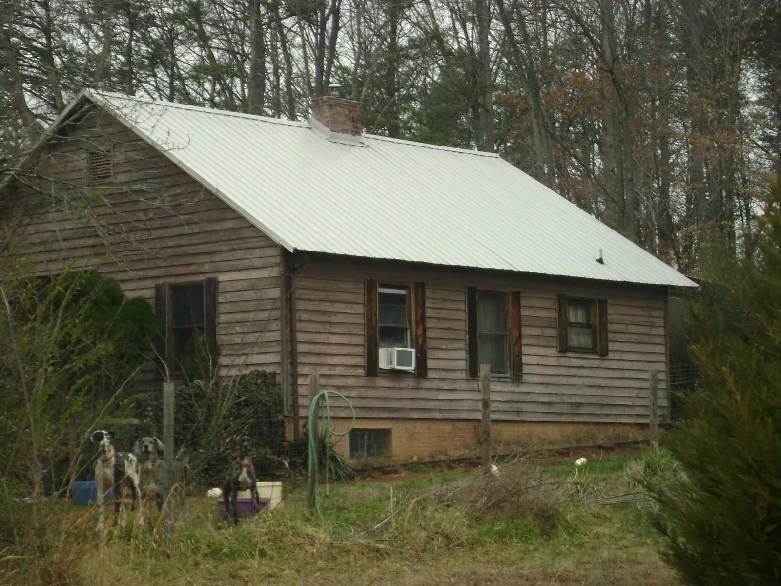 White metal roof on an old wood sided farmhouse, from a Metal Roof Installation job in Kemah
