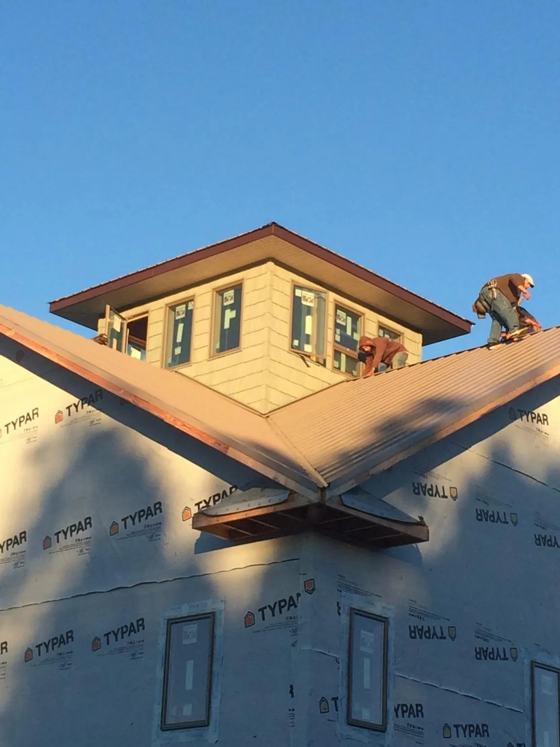 Roofers working around a rooftop cupola on a new metal roof at sunset — Roof Waterproofing in Kemah by Roofing Brothers